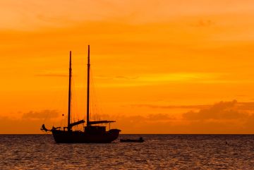 Sailboat anchored nearby, sun setting